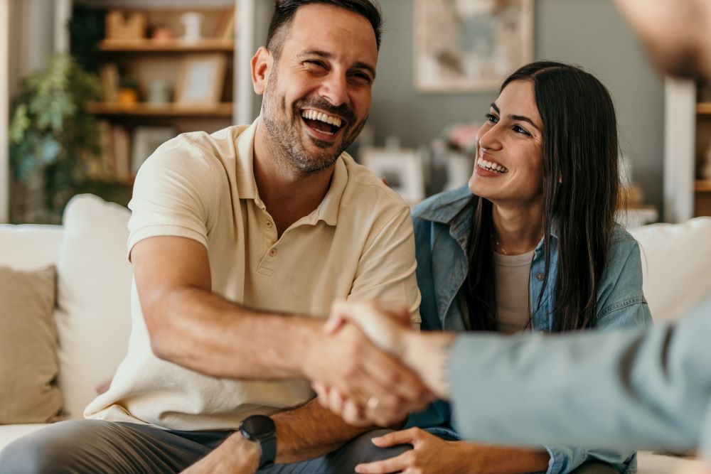 Man shaking hands with an advisor with his wife sitting next to him