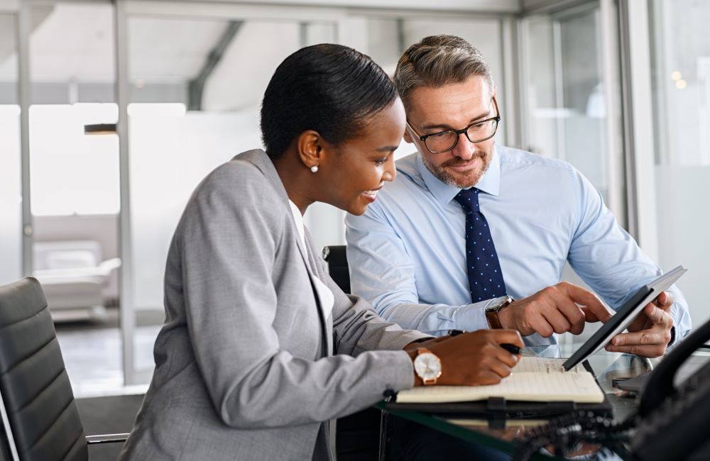 Two colleagues discussing something while looking at their laptop 